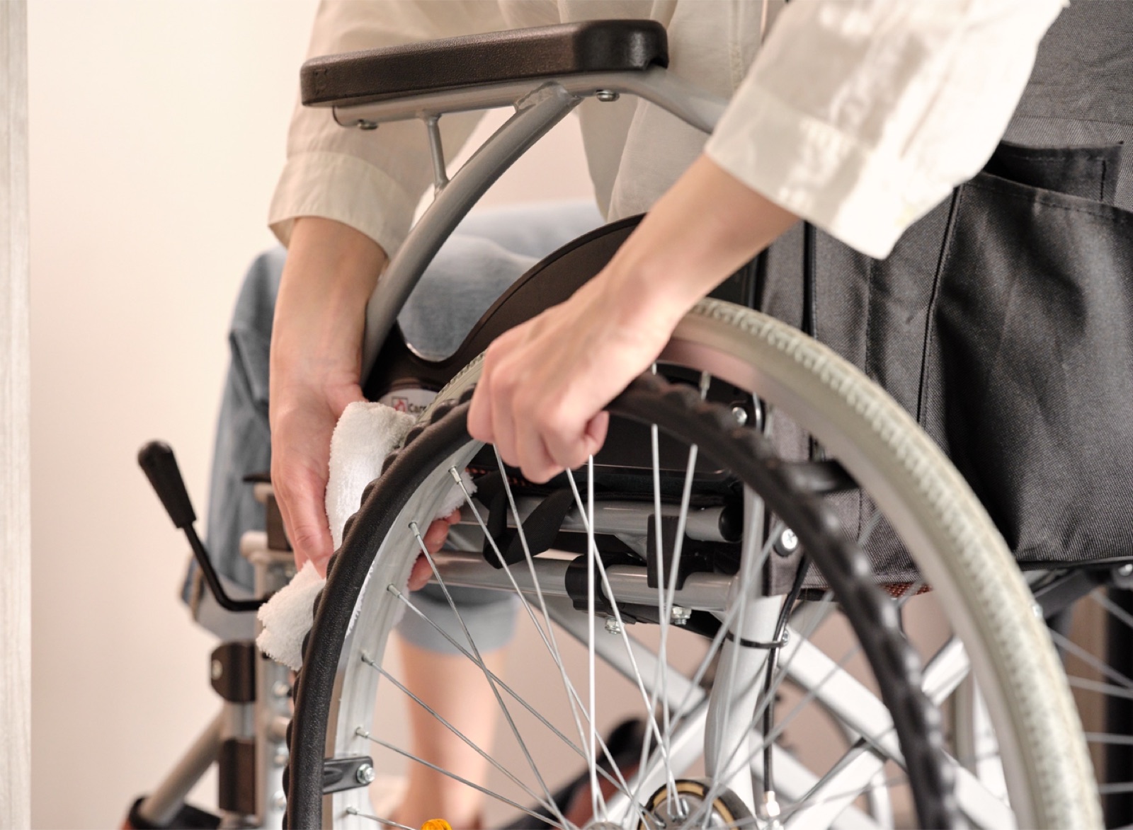 車いすに座ったままタイヤを回しながら雑巾で拭き取る様子